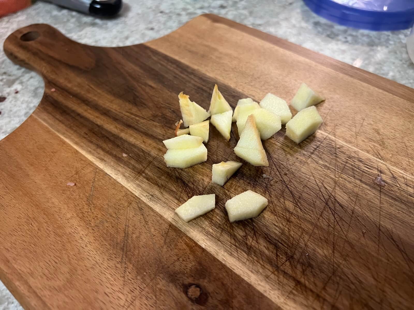 Diced pieces of Gala apple on a wooden cutting board